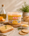 A tub of El-Batal Creamy Cheese Spread displayed on a wooden board with bread, crackers, cheese, and a bottle of oil in a warm, styled setting.